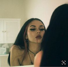 a woman with blood on her face looking in the mirror