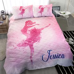 a bed with a pink and blue cover that has a ballerina design on it