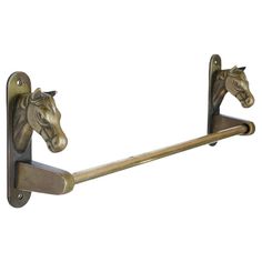 two horse head hooks are attached to a metal wall mounted toilet roll dispenser