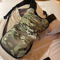 a duffle bag sitting on top of a bed next to a pillow and book