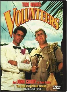 two men standing next to each other in front of an advertisement for the movie volunteers