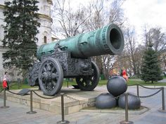 a large green cannon sitting on top of a stone slab in front of a building