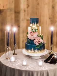 a three tiered cake sitting on top of a table next to some lit candles