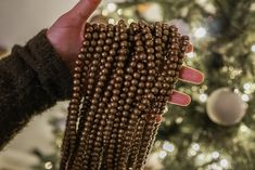 a hand holding beads in front of a christmas tree