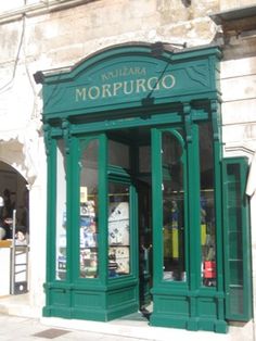 an old building with green doors and windows on the street corner in front of it