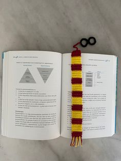 an open book with a red and yellow tassel on top of it next to scissors