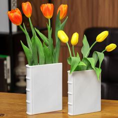 two white vases with yellow and orange flowers in them