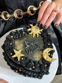 a woman is holding a cake decorated with gold stars and crescent moon decorations on it