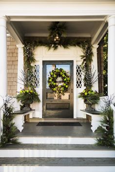 the front porch is decorated with greenery and wreaths