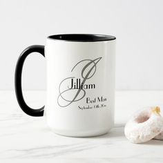 a white and black coffee mug next to a donut