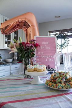 a table topped with cupcakes and cake covered in sprinkles next to a pink balloon