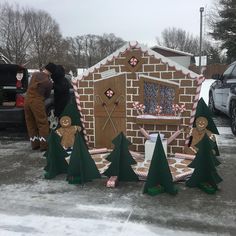 two people standing in front of a building made out of cardboard trees and candy canes