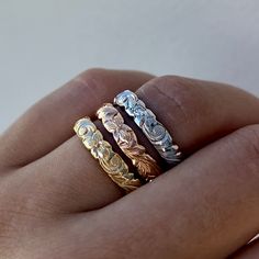 a person's hand with three different rings on their fingers, one is gold and the other is silver