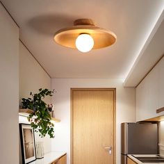 a kitchen with wooden cabinets and stainless steel appliances in the center is lit by a round light fixture