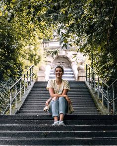 a woman sitting on the steps in front of some trees