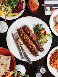 a table topped with plates filled with different types of food and utensils next to each other