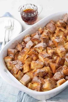 a white casserole dish filled with bread and powdered sugar on a table