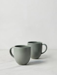 two gray cups sitting on top of a white table