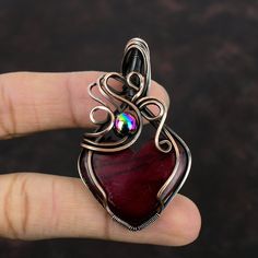 Note : Due to the natural formation of this gemstone. Slight variation in design and color are to be expected.  Red Fire Labradorite Pendant Copper Wire Wrapped Pendant Copper Gemstone Jewelry Designer Pendant Handmade Wire Wrap Jewelry Gifts For Mom Handmade Copper Pendant SKU : VFWP-4410 Gemstone : Red Fire Labradorite Stone Shape : Heart    Metal Purity : Copper Pendant Length : 63 MM   Pendant Width : 37 MM Labradorite has many physical benefits - grab this crystal to relieve arthritis, boost your metabolism and immune system, ease chest infections and cold/flu symptoms. This crystal is also said to regulate hormones, reduce PMS, ease gout and lower blood pressure. Artisan Wire Wrapped Red Jewelry, Artisan Red Wire Wrapped Jewelry, Wire Wrapped Ruby Jewelry Gift, Ruby Wire Wrapped Jewelry Gift, Ruby Wire Wrapped Jewelry As Gift, Artisan Red Agate Jewelry, Wire Wrapped Ruby Jewelry For Crafting, Red Agate Pendant Jewelry, Unique Handmade Ruby Necklaces