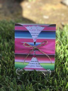 a card with a ribbon tied to it sitting in the grass