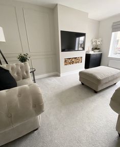 a living room with white furniture and a flat screen tv