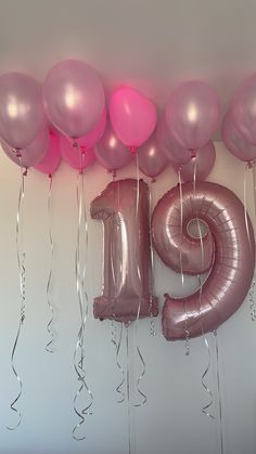 balloons and streamers in the shape of numbers are hanging on a wall with helium