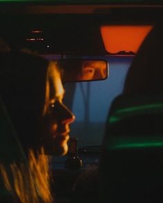 two people sitting in the back seat of a car at night, one is looking out the window