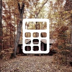 a house in the woods surrounded by trees and leaves with a large white cutout over it