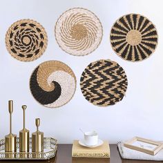 four woven baskets hanging on the wall next to a coffee cup and vase with gold accents