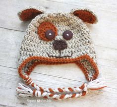 a crocheted bear hat with brown eyes and ears is laying on the floor