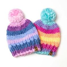 two knitted beanies sitting next to each other on top of a white surface