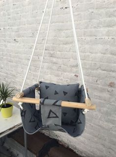 a grey and white swing chair with black triangles on the back, sitting next to a potted plant