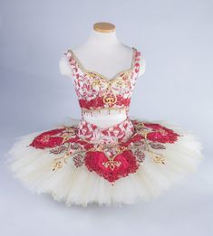 a red and white tutu with gold trimmings on the bottom, in front of a mannequin