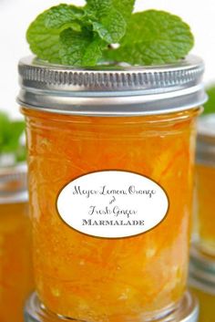 a jar filled with orange marmalade sitting on top of a table next to other jars