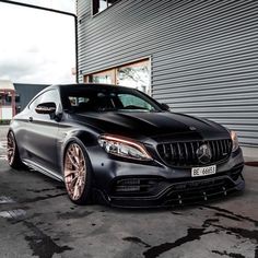 a black mercedes s - class parked in front of a building with chrome rims