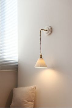 a white wall with a lamp on it next to a pillow