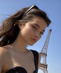 a woman standing in front of the eiffel tower with her hair blowing in the wind