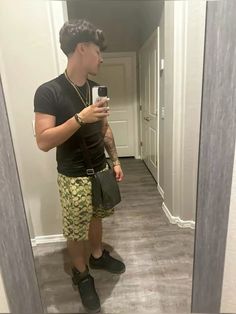 a man taking a selfie in the mirror with his cell phone while wearing shorts