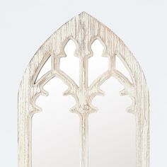 a white wooden window frame with an arched mirror on the front and back sides, all made out of wood