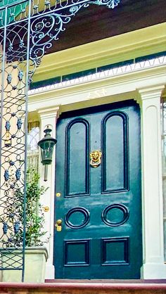 a green door is on the side of a house with wrought iron railings and potted plants