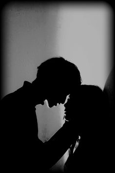 black and white photograph of a man kissing a woman's head in the dark