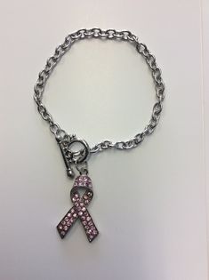 Proudly display your ribbon of hope. Our crystal pink ribbon bracelet is simple and elegant. *Silvertone * Crystal Accents Pink Ribbon Jewelry Gift, Pink Adjustable Crystal Bracelet With Rhinestones, Adjustable Pink Hand-strung Wrap Bracelet, Pink Hand-strung Spiritual Rosary Bracelet, Adjustable Pink Ribbon Necklace, Ribbon Bracelets, Toggle Bracelet, Pink Ribbon, Cross Necklace