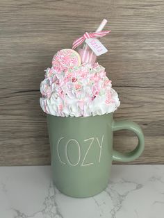 a green cup filled with pink and white frosted cake on top of a counter