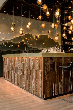 a bar with lights hanging from it's ceiling and two stools in front of the bar