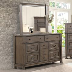 a bedroom scene with focus on the dresser and mirror, which has been placed in front of a stone wall