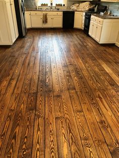 an empty kitchen with wood floors and white cabinets