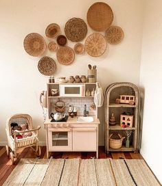 a kitchen with lots of wicker baskets on the wall and rugs around it