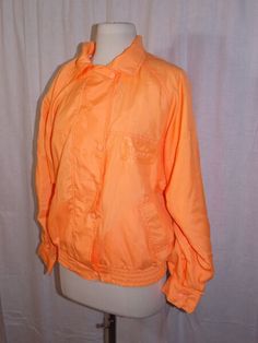 Click to Enlarge   ELLESSE Vtg 80s Orange LINED WINDBREAKER JACKET S All Sports Warm Up NWT NOS NEW Welcome !! To browse our entire store inventory CLICK HERE. ITEM:  Vintage 1980s New Old Stock with the original tags, women's athletic warm up / windbreaker jacket.  Ellesse label.  Bright orange color, outer shell is 100% nylon.  Front zip down with outer snaps.  Puffy Ellesse logo with ball on the left chest, and sport ball logo design across the back. Two outer pockets.  Comfortable elastic wa Retro Sports Windbreaker With Pockets, Vintage Windbreaker For Fall Sports, Retro Spring Track Jacket For Outdoor, Vintage Spring Sports Windbreaker, Retro Spring Track Jacket For Sports, Retro Track Jacket For Spring Sports, Vintage Track Jacket With Pockets For Spring, Retro Spring Windbreaker With Pockets, Retro Windbreaker With Pockets For Spring