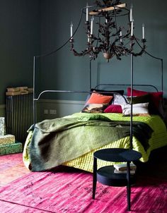 a chandelier hanging over a bed in a room with grey walls and furniture