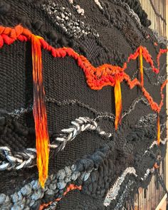 a close up of a piece of art with orange and black yarn on it,